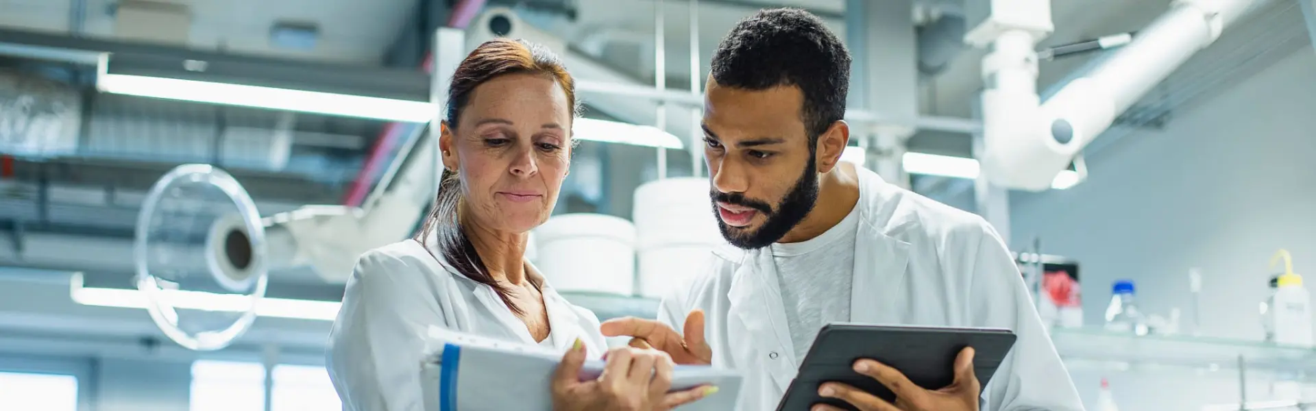 Two professionals, a man and a woman, discussing data in a laboratory setting.